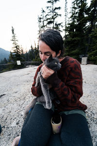 Side view of young woman holding and loving on her cat