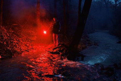 Man standing in illuminated red fire at night