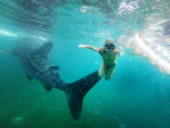 Woman swimming by fish in sea