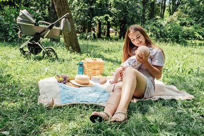 Mother and newborn baby in stroller on summer park. happy young woman mother taking care of baby in