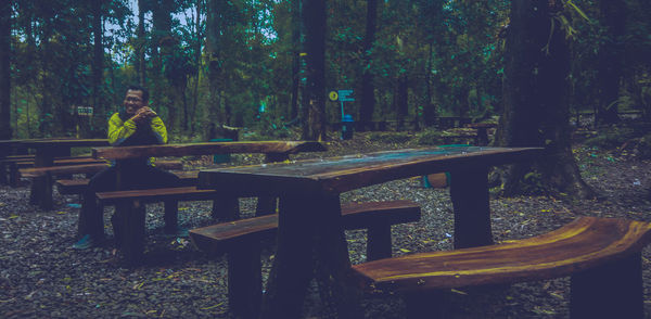 Woman sitting on table in forest