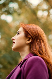 Autumn portrait of candid beautiful red-haired girl with fall leaves in hair.