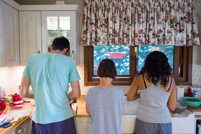 Rear view of friends preparing food in kitchen