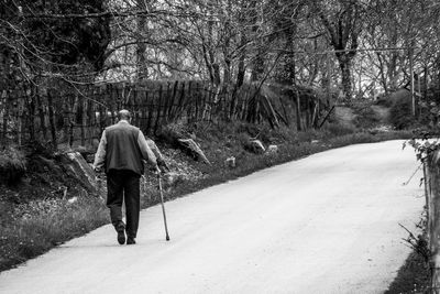 Rear view of man walking on snow covered footpath