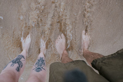 Low section of man on sand at beach