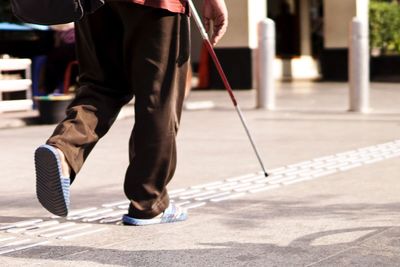 Low section of man walking on tactile paving in city