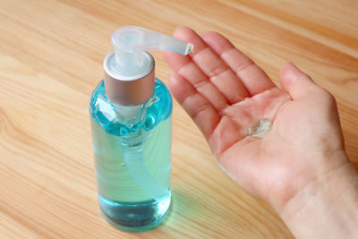 Cropped image of person washing hand with sanitizer over table