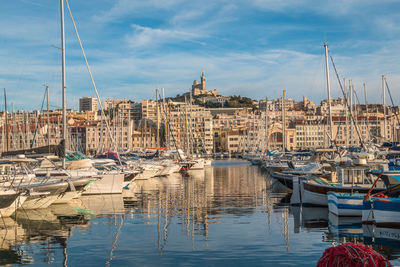 Sailboats moored in harbor against buildings in city