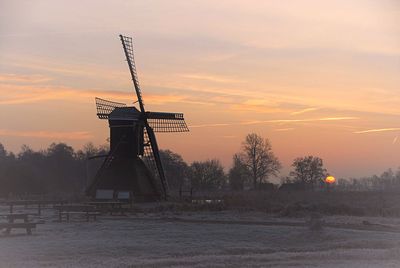 Silhouette of windmill on field at sunset