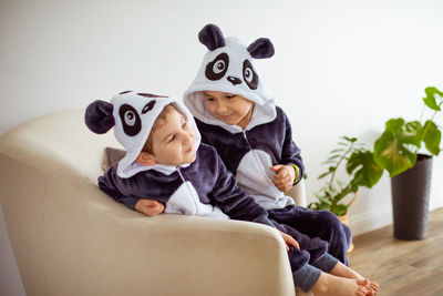 Cute siblings sitting on sofa at home