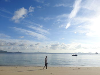 Man walking at shore of beach against sky