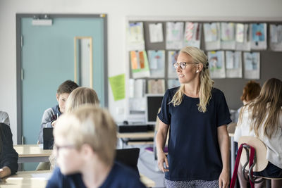 Teacher standing amidst students in classroom at school