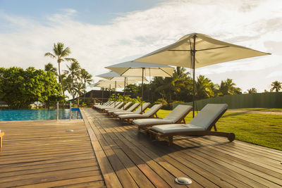 Chairs by swimming pool against sky