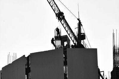 Low angle view of crane at construction site against clear sky