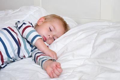 Sleeping child in bed. cute little kid sleeps on white blanket on its side, lying during day sleep