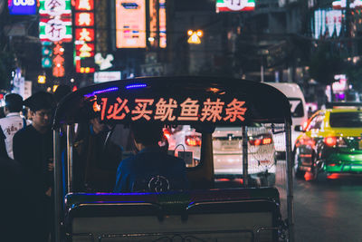 People on illuminated street in city at night