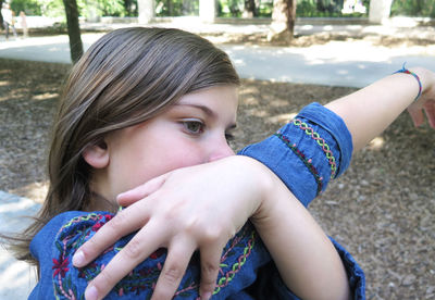 Close-up of girl with hand raised standing in park