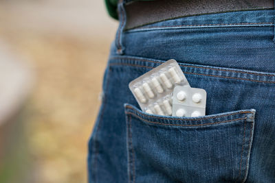 Cropped image of person with medicines in pocket