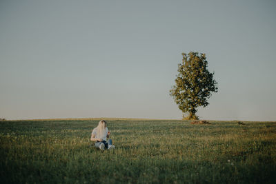 Wide angle view of a woman sitting in a field