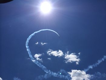 Low angle view of sun shining through blue sky