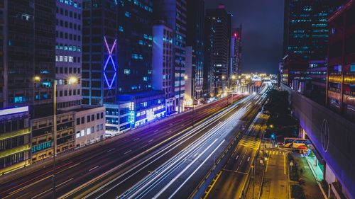 Light trails on road along illuminated buildings