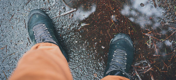 Man standing during rainy autumn weather in a puddle in a waterproof tracking shoes.