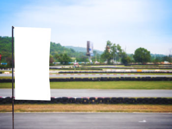 Empty road sign on field against sky