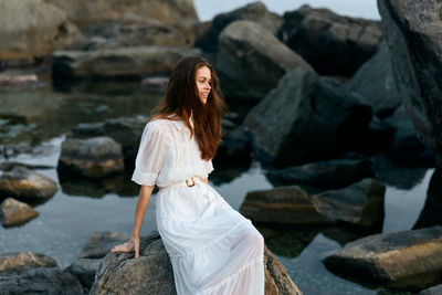 Side view of young woman sitting on rock