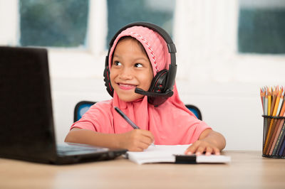 Portrait of a smiling girl sitting on table