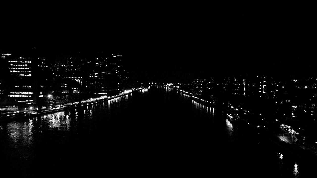 ILLUMINATED BRIDGE OVER RIVER AT NIGHT