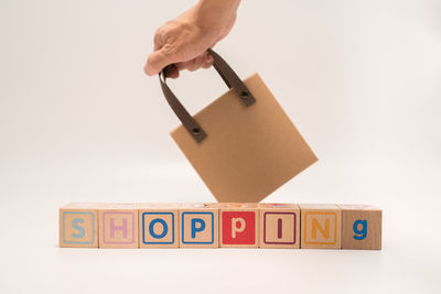 Cropped hand holding toy blocks against white background