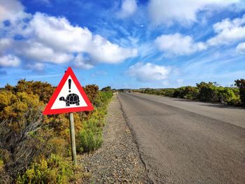 Information sign by road against sky