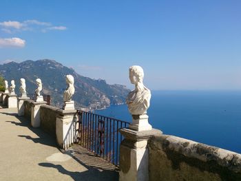 Statues by sea against clear sky