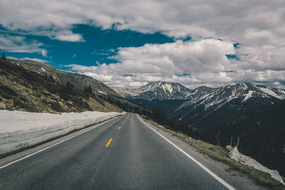 Road amidst snowcapped mountains against sky