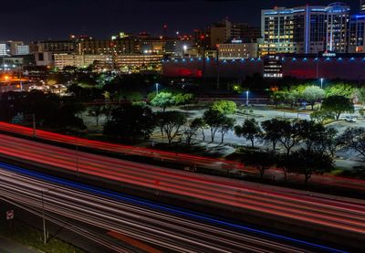 Light trails on road by illuminated city at night