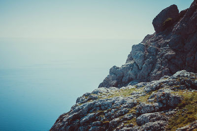 Rock formation by sea against sky