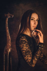 Portrait of young woman holding camera at night