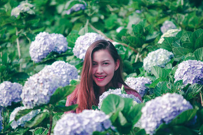 Portrait of smiling young woman against plants