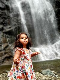 Portrait of woman standing on rock against waterfall