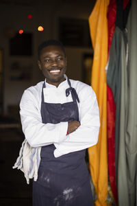 Smiling chef with arms crossed standing at doorway of restaurant