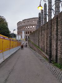 People walking in historic building against sky