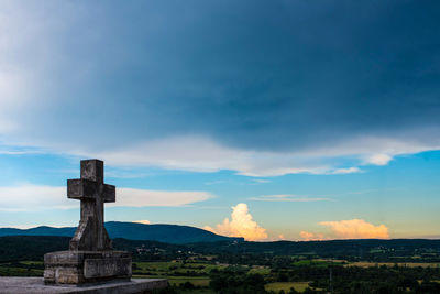 Cross on landscape against sky