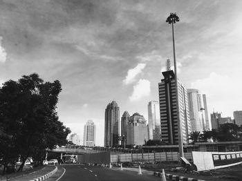 Road by buildings in city against sky