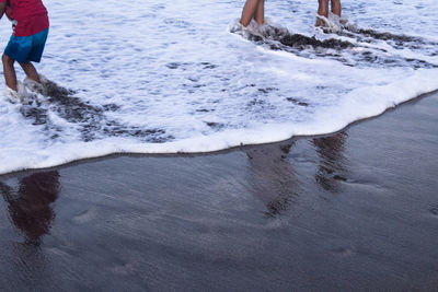 Low section of people walking on beach