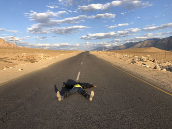 Teenage boy lying on road at desert