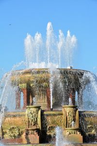 Fountain in front of built structure against clear sky