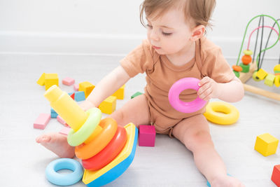 Cute baby girl playing with pyramid and wooden toys at home. early children development