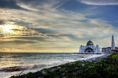 View of building by sea against cloudy sky