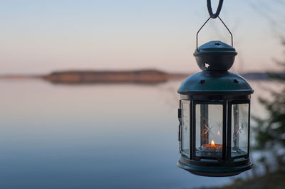 Illuminated lamp post in lake against sky