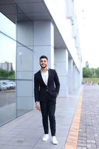 Young businessman standing against building